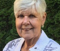 Smiling woman with short gray hair outdoors.
