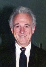 Smiling man in a suit with gray hair.