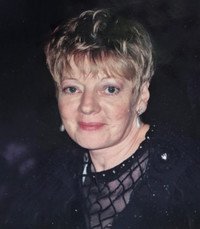 Woman smiling with short blonde hair in black dress.