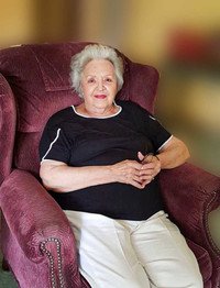 Elderly woman sitting in a comfortable chair indoors.