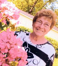 Smiling person beside pink flowers outdoors.