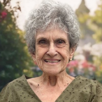Smiling elderly woman in garden setting.