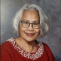 Elderly woman smiling, wearing glasses and red sweater.