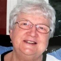 Smiling elderly woman with glasses and white hair.