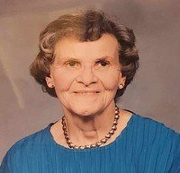 Smiling elderly woman with short hair and necklace.