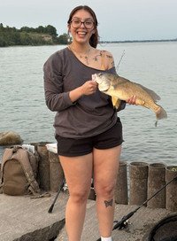 Person holding a fish by the water