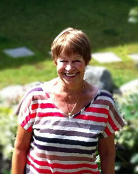 Smiling woman outdoors in striped shirt.