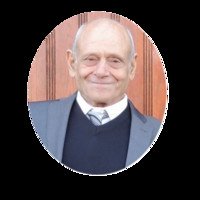 Elderly man in suit smiling with wooden background.