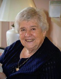 Smiling elderly woman sitting indoors.