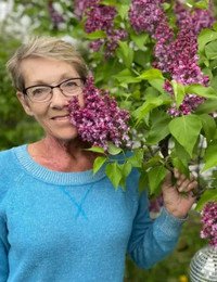 Smiling person with lilac flowers in garden