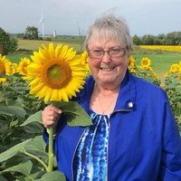 Smiling woman standing in a sunflower field.