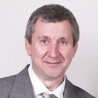 Smiling man in a gray suit and tie.