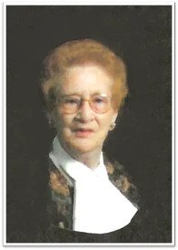 Portrait of an elderly woman with glasses and scarf.