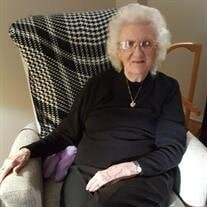Elderly woman sitting in a chair, smiling indoors.