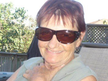 Smiling woman wearing sunglasses outdoors.