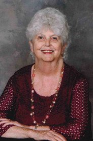 Smiling elderly woman with white hair and necklace.