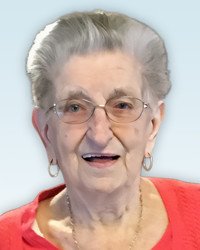 Smiling elderly woman with glasses and red sweater.
