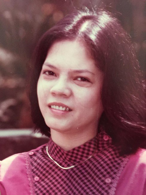 Portrait of a woman in checkered blouse, smiling.