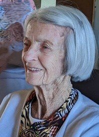 Elderly woman smiling, short gray hair, printed shirt.