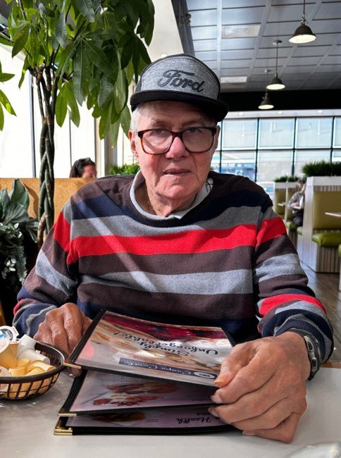 Man in striped sweater holding menu at restaurant.