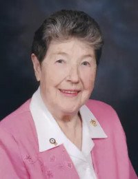 Smiling elderly woman in pink jacket, studio portrait.
