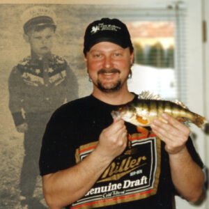 Man smiling, holding a fish indoors.