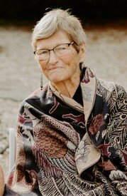 Elderly woman smiling, wearing patterned shawl.