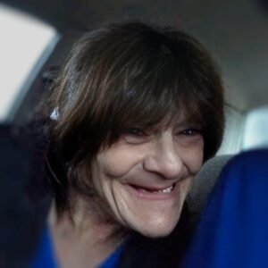 Smiling person with dark hair in a car