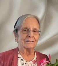Elderly woman with flowers smiling warmly.