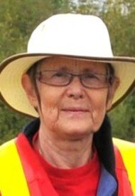 Person wearing hat and safety vest outdoors.