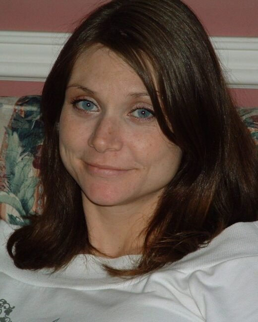 Person sitting on floral couch, smiling.