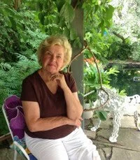 Woman seated in garden with sculpture and pond