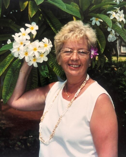 Smiling woman holding frangipani flowers in garden.