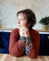 Woman sitting at table, looking sideways.
