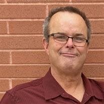 Smiling man in maroon shirt against brick wall