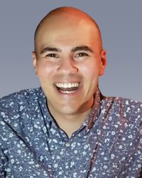 Smiling person in floral shirt on gray background.