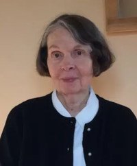 Elderly woman with gray hairstyle in black sweater.