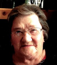 Elderly woman smiling indoors in natural lighting.