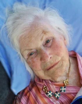 Elderly woman smiling, wearing a striped shirt