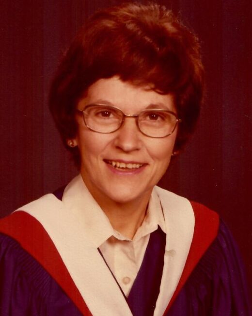 Graduate smiling in academic regalia and glasses.