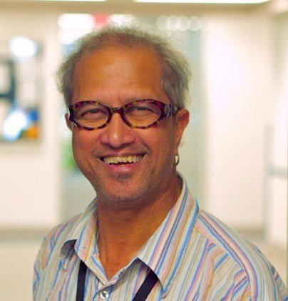 Smiling person wearing glasses and striped shirt indoors.