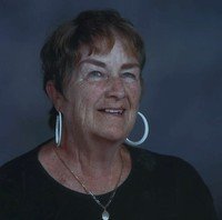 Smiling woman with short hair and hoop earrings.