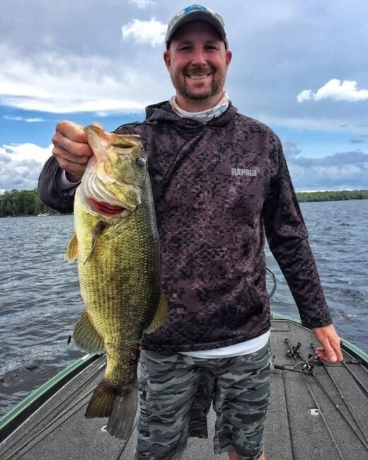 Man holding large fish on boat deck.