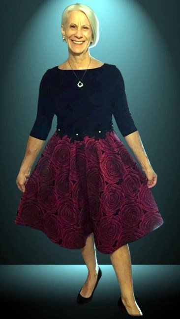 Smiling woman in black top and red floral skirt.