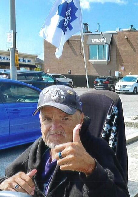 Man giving thumbs-up in urban setting with flag.
