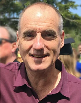 Smiling person outdoors in sunlight.
