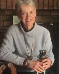 Person smiling, holding an award, sitting indoors.