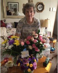 Woman smiling with colorful flower bouquets on table.