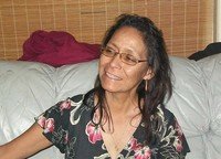 Smiling woman sitting on a couch in glasses.