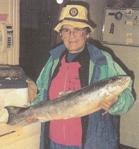 Person holding large fish indoors, smiling.